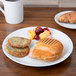 A grilled sandwich and fruit on a white Arcoroc Candour porcelain plate on a table.