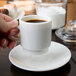 A person holding an Arcoroc saucer with a cup of coffee.