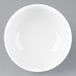 An Arcoroc white porcelain bowl on a gray surface.