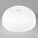 An Arcoroc white porcelain bowl on a gray background.