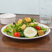 A Chef & Sommelier white bone china plate with a salad, croutons, and cucumber.