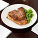 A piece of meat and a salad on a white Chef & Sommelier bone china plate.