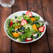 A white Arcoroc deep coupe plate with a salad of strawberries, blueberries, and oranges.