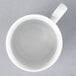 An Arcoroc white porcelain mug with a handle full of liquid.