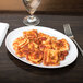 A white oval porcelain platter with a plate of ravioli and a fork.