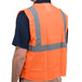 A person wearing a Cordova orange high visibility safety vest with reflective stripes.