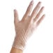 A hand wearing a Noble Products clear plastic glove.