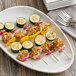 A plate of chicken and vegetable skewers on a table.