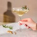 A hand holding a stem of a Chef & Sommelier champagne coupe glass.