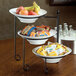 An American Metalcraft round melamine serving bowl filled with apples on a hotel buffet counter.