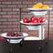 A white American Metalcraft melamine bowl on a table with red apples and oranges.