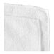 A close-up of a white Carlisle microfiber cleaning cloth with a folded edge.