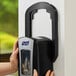 A person holding a black GOJO True Fit wall plate for a LTX-12 hand soap dispenser.