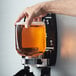 A hand using GOJO FMX Fresh Fruit foaming hand soap in a dispenser.