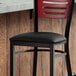 A Lancaster Table & Seating black vinyl padded seat on a metal frame.