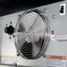A metal fan with a warning sticker on it inside a Beverage-Air back bar refrigerator.