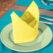 A yellow Intedge cloth napkin folded on a plate.