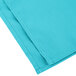 A folded teal cloth napkin.