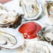 A CAC white china oyster plate with oysters and red sauce.