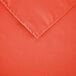 An orange square polyester cloth table cover with a hemmed edge.
