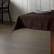 A brown Intedge square tablecloth on a restaurant table.