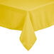 A yellow rectangular polyester table cover with hemmed edges on a table.