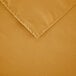 A close-up of a gold rectangular polyester table cover with hemmed edges.