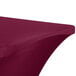 A burgundy Snap Drape Contour Spandex table cover with a curved edge on a table.