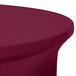 A burgundy Snap Drape Contour table cover with a round edge on a table.