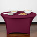 A table with a burgundy Snap Drape Contour cover and plates of food on it.