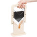 A hand holding a beige plastic Baker's Mark bagel slicer.