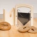 A Baker's Mark beige bagel slicer on a table with a sliced bagel inside.