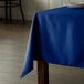 A royal blue Intedge rectangular tablecloth on a wooden table.