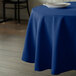 A blue Intedge tablecloth on a table with a white plate on it.