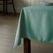 A rectangular table with a seafoam green Intedge tablecloth on it.