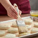 A person using an Ateco boar bristle brush to baste food.