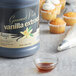 A bottle of Regal Gourmet Pure Vanilla Extract next to a cupcake with white frosting.