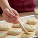 A person using an Ateco round bristle pastry brush to paint food.