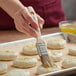 A person using an Ateco boar bristle brush to baste food.