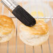 A Ateco round boar bristle pastry brush brushing a pastry.