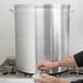 A man using a Vollrath Wear-Ever aluminum stock pot faucet to pour liquid into the pot.