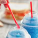 A person holding a Choice red jumbo spoon straw in a cup of blue liquid.