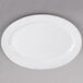 A Tuxton bright white oval china platter on a gray surface.