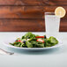 A Minski white melamine plate with a spinach salad with strawberries and blueberries.