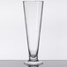 A clear GET Tritan plastic footed pilsner glass on a table.