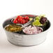 An American Metalcraft galvanized metal tub filled with sliced onions and tomatoes on a counter.