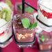 A black tower dessert shot display stand holding chocolate pudding cups with chocolate sauce and berries.