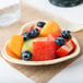 A heart-shaped palm leaf plate with fruit on a table.