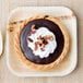 A chocolate dessert with whipped cream and nuts on an Eco-gecko palm leaf plate.