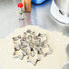 A stainless steel snowflake cookie cutter cutting snowflake shapes out of dough.